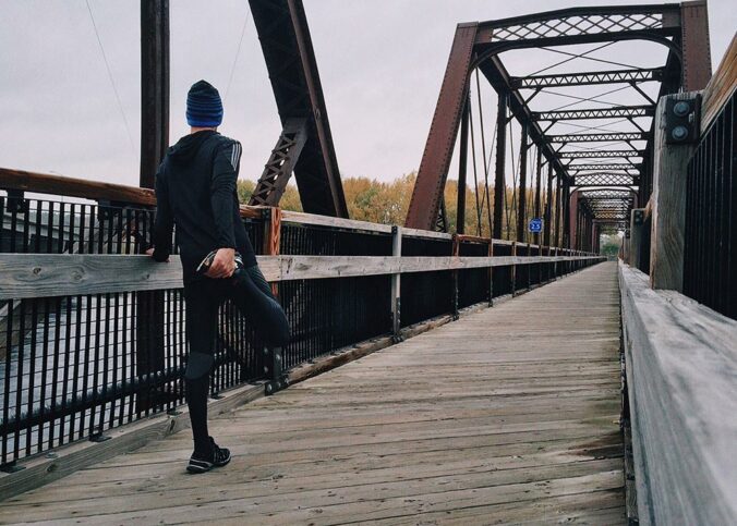 Man stretching on a wooden bridge before a run
