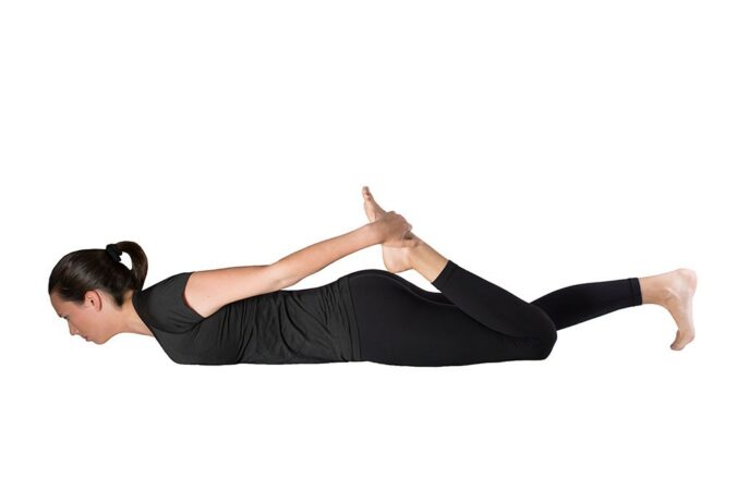 Woman doing quad stretch lying prone with left hand grabbing left foot to pull to butt